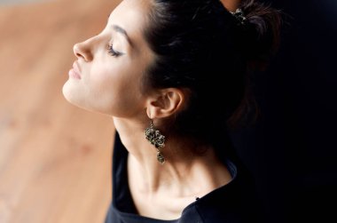 Siyah elbiseli güzel esmer, yakın plan poz veriyor.