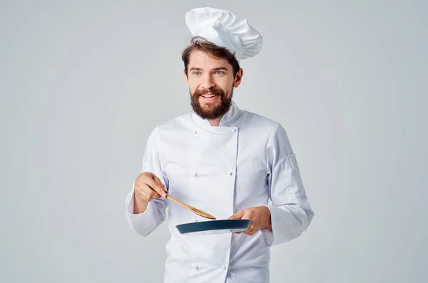 Um homem de uniforme de chefs com uma frigideira na mão Profissional — Fotografia de Stock