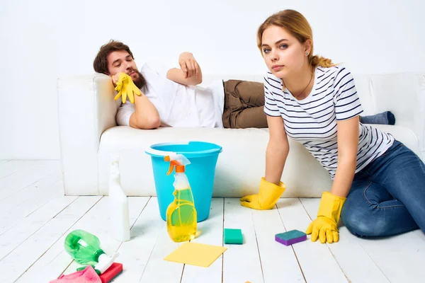 Una pareja joven cerca del sofá artículos de limpieza guantes de protección — Foto de Stock