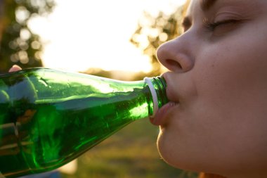 Yeşil bir şişeden su içen güzel bir kadın.