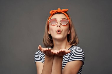 Güneş gözlüklü, çizgili, turuncu saç bandı takan kadın.