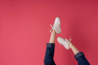 Beyaz spor ayakkabılı kadın bacakları pembe arka plan pozu