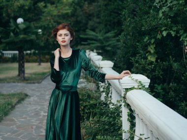 Park 'ta yeşil elbiseli bir kadın romantik bir yürüyüş yapıyor.