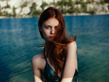 Yeşil mayo giymiş kızıl saçlı güzel bir kadın. Lüks modellik yapıyor.