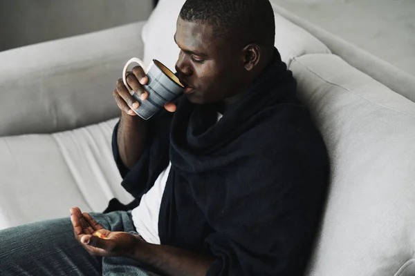 Африканский американец с чашкой в руке сидит на диване сверху — стоковое фото