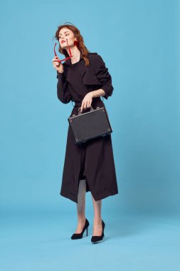 Siyah ceketli, güneş gözlüğü takan iş kadını. Profesyonel, zarif, mavi arka plan.