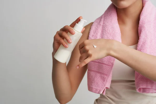 Mulher com toalha rosa nos ombros aplicar creme no cuidado do corpo da pele — Fotografia de Stock