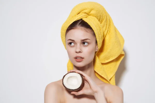 Femme aux épaules nues serviette jaune sur sa tête noix de coco tenant fruits peau propre — Photo