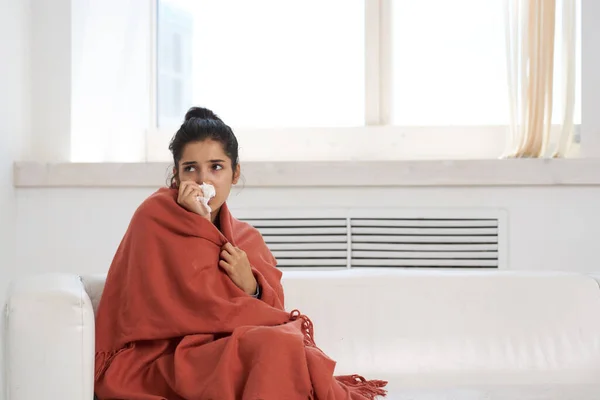 woman sitting at home covered with a blanket health problems cold