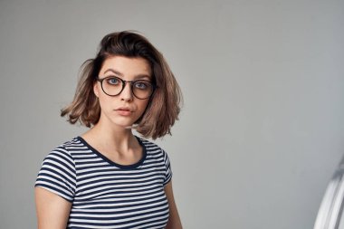 Çizgili tişörtlü, hafif arka planlı güzel bir kadın.