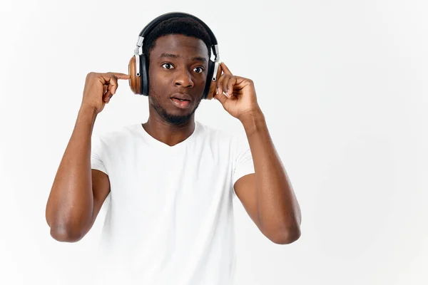 Homem de aparência africana em camiseta branca com fones de ouvido ouvindo música — Fotografia de Stock