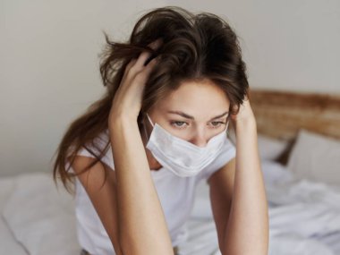 Tıbbi maskeli kadın elleriyle kafasına dokunuyor yakın çekim oda modeli