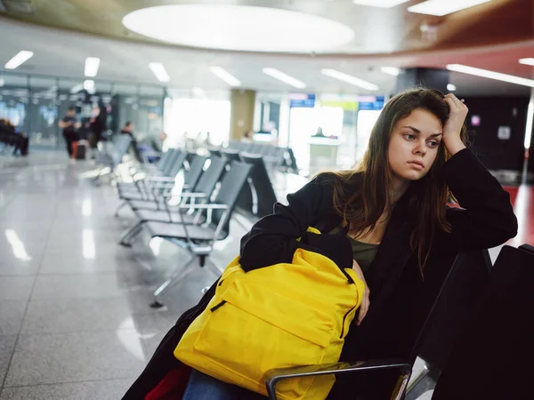 Γυναίκα με λυπημένη έκφραση του προσώπου αεροδρόμιο αναμονή κίτρινο σακίδιο — Φωτογραφία Αρχείου