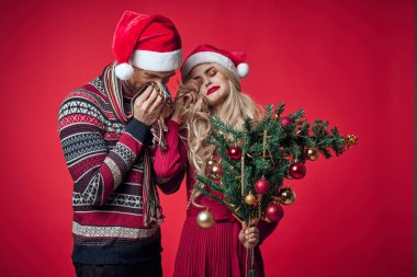 Genç çift Noel 'i birlikte kutluyor. Dekorasyon kırmızı arka plan.