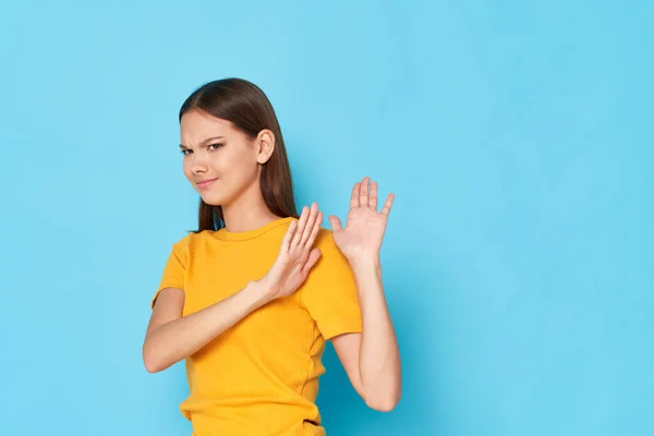 Mulher em uma camiseta amarela com nojo virou-se para o lado e gesticulates com as mãos em um fundo azul — Fotografia de Stock