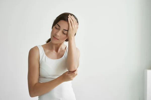 Kobieta w białym t-shirt trzymając jej problemy ze zdrowiem głowy depresja migrena — Zdjęcie stockowe