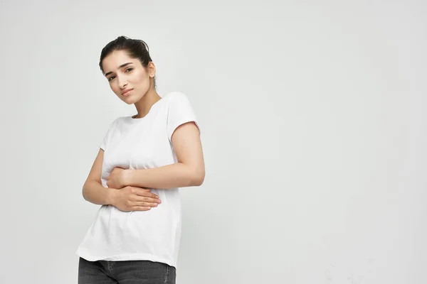 Brunette in white t-shirt holding her belly menstruation health problems dissatisfaction — Stock Photo, Image