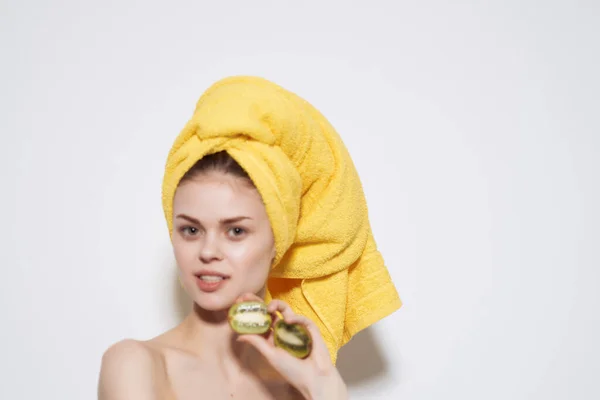 Bella donna con asciugamano giallo sulla testa spalle nude kiwi frutta — Foto Stock