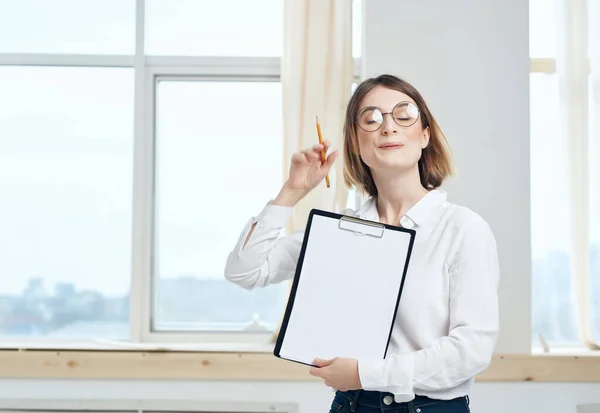 Donna d'affari in camicia bianca e occhiali vicino alla finestra dell'ufficio — Foto Stock