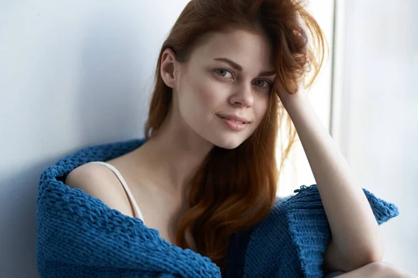 Mujer bonita sentada en el alféizar de la ventana con una sonrisa a cuadros azul —  Fotos de Stock