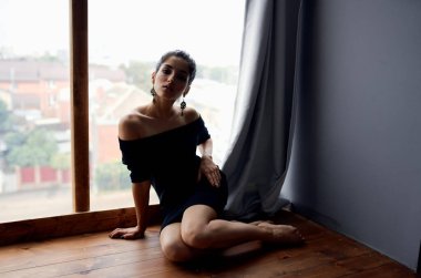 Pencere kenarındaki güzel kadın çekici bir poz veriyor. Küpeler zarif bir tarz.