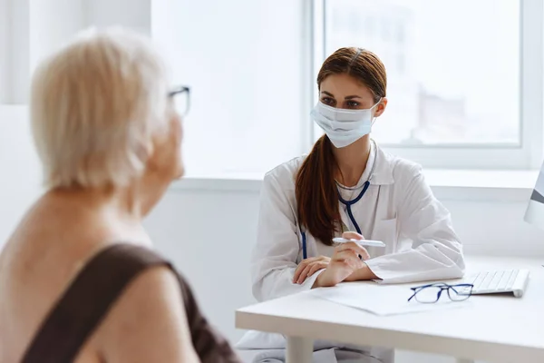 마스크를 쓰고 있는 연로 한 여자는 의사의 건강 관리와 의사소통을 한다 — 스톡 사진
