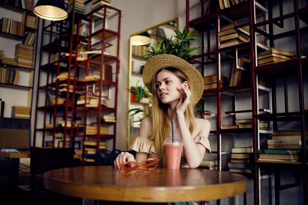 Mujer alegre sentada en una mesa con una bebida en un café recreación —  Fotos de Stock
