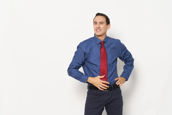 Um homem em uma camisa azul e em uma gravata vermelha calças modelo de fundo leve — Fotografia de Stock