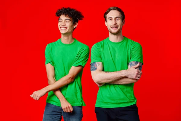 Dos amigos verde camisetas comunicación estilo de vida rojo fondo — Foto de Stock