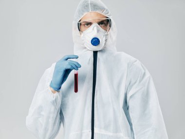 Doktor, elinde küçük bir şişeyle tıbbi kıyafetli. Sıvı enfeksiyonu Coronavirus.