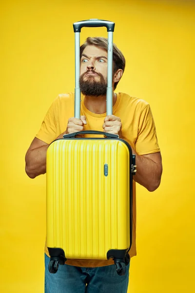 Férfi támaszkodik könyökét egy sárga bőrönd a kezét utazási turizmus — Stock Fotó