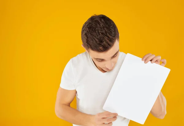 Homme en t-shirt blanc feuille blanche de présentation papier fond jaune — Photo