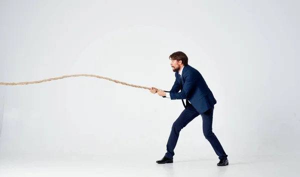 A man in a suit pulls the rope career office light background — Stock Photo, Image