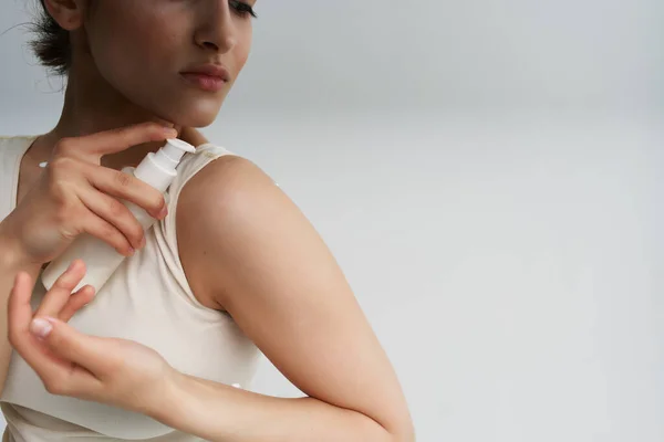 Kvinna i vit t-shirt applicerar kräm på huden närbild — Stockfoto