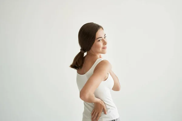 Mulher em branco t-shirt dor nas articulações tratamento saúde luz fundo — Fotografia de Stock