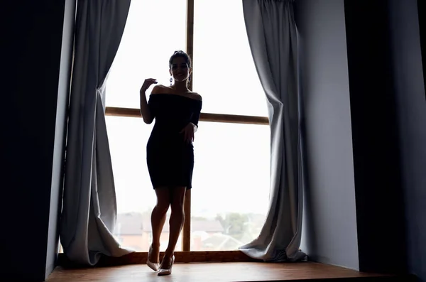 Kvinna siluett nära fönster interiör poserar modell — Stockfoto