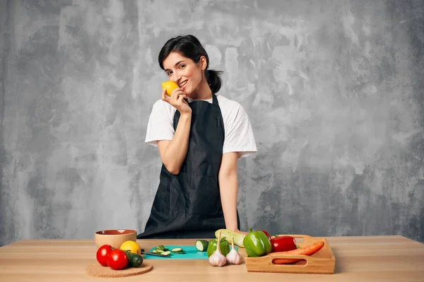 Femme en tablier noir déjeuner à la maison végétarienne planche à découper — Photo