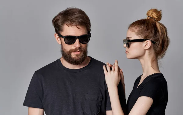 Um jovem casal em preto t-shirt óculos de sol posando isolado fundo — Fotografia de Stock