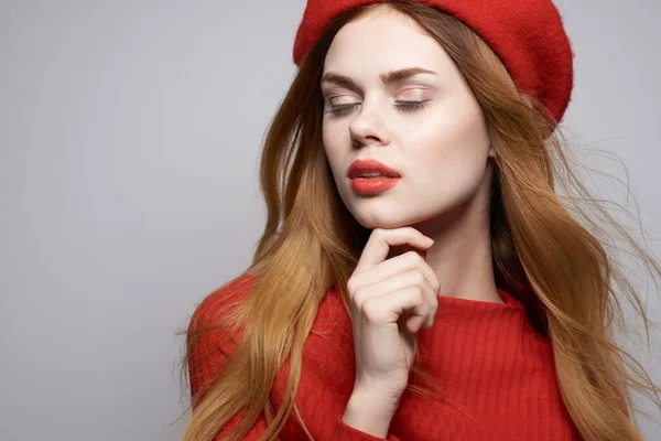 Mulher alegre com um boné vermelho em sua cabeça glamour luz fundo — Fotografia de Stock