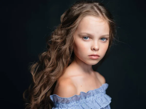 Menina com penteado no vestido posando fundo escuro — Fotografia de Stock