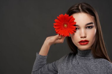 Esmer, kırmızı çiçekli, parlak makyajlı, esmer bir kadın.