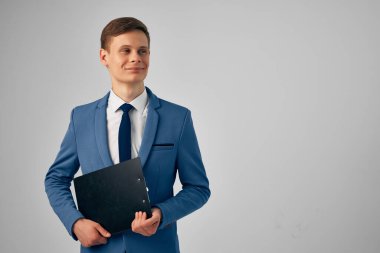 Elinde siyah bir klasör olan takım elbiseli müdür özgüvenini belgeleyecek.
