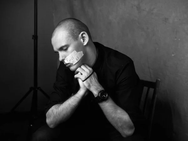 Homem careca em camisa preta senta-se na cadeira de estúdio — Fotografia de Stock
