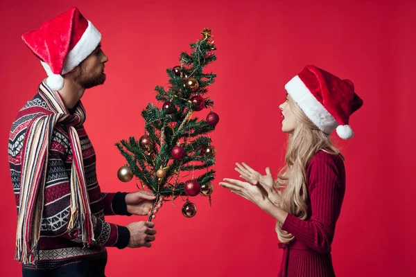 Fröhliches junges Paar mit Nikolausmützen Weihnachtsbaumschmuck — Stockfoto