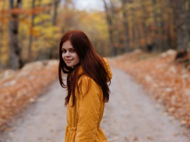 Sonbahar orman yürüyüşünde sarı ceketli kadın.