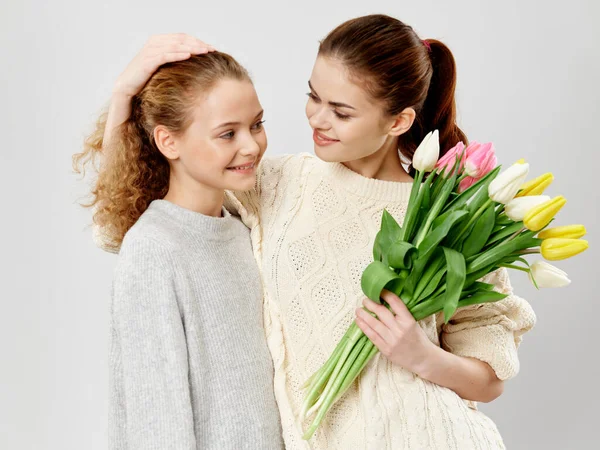 Mulher com um buquê de flores e uma menina em um fundo leve vista cortada — Fotografia de Stock