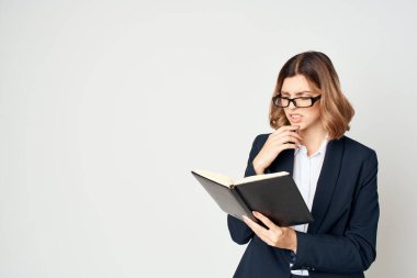 Elinde not defteri olan takım elbiseli bir iş kadını stüdyo ofisini belgeleyecek.