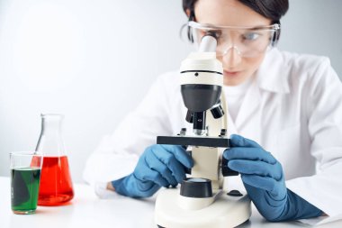 Bir kadın mikroskop kimyasal çözelti laboratuvarı araştırma biyoteknolojisine bakıyor.