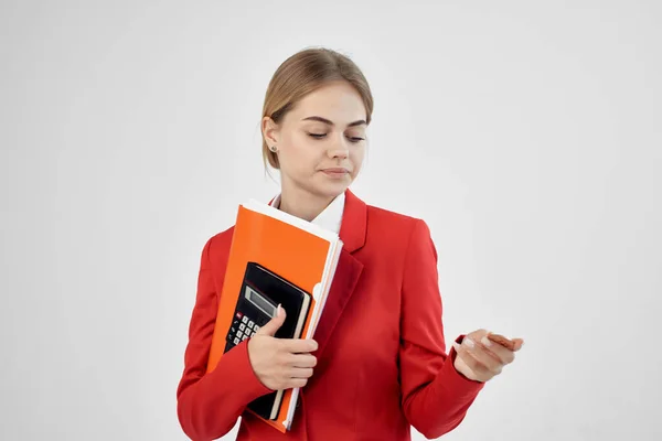 Zakenvrouw in een rood jasje met documenten in de hand lichte achtergrond — Stockfoto