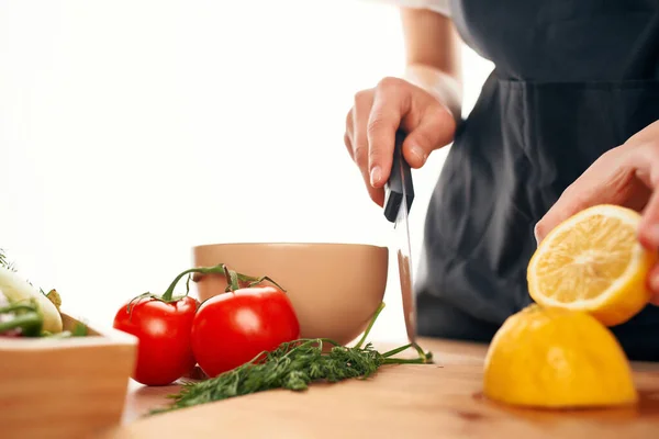 Chef con un coltello in mano taglia verdure e cucina casalinga al limone — Foto Stock
